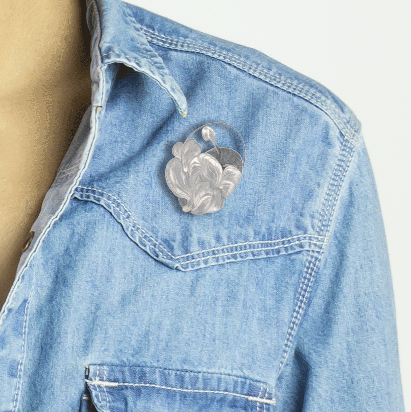 A close-up image of the 'Cameo of a Wildflower' brooch, showcasing textured layers of hand-chased and repoussed wildflower forms in sterling silver. This simple yet alluring statement piece measures 2 x 1-3/4 inches and is crafted by the artist in British Columbia.